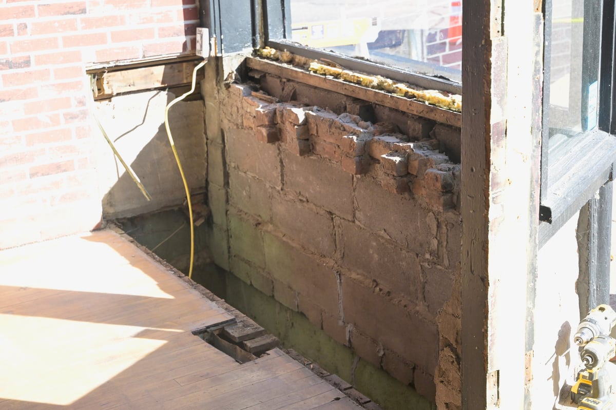 Construction debris and rusty metal dumpster against the brick wall of the brewery being repaired after the vehicle impact