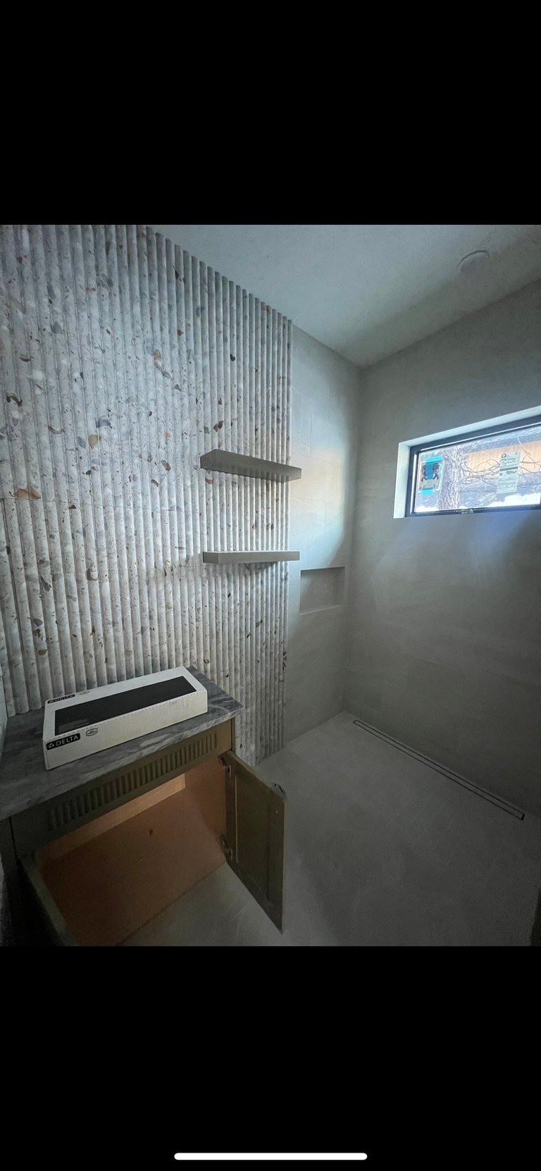 Modern bathroom interior with white textured wall, floating shelves, white vanity, and small window with decorative art