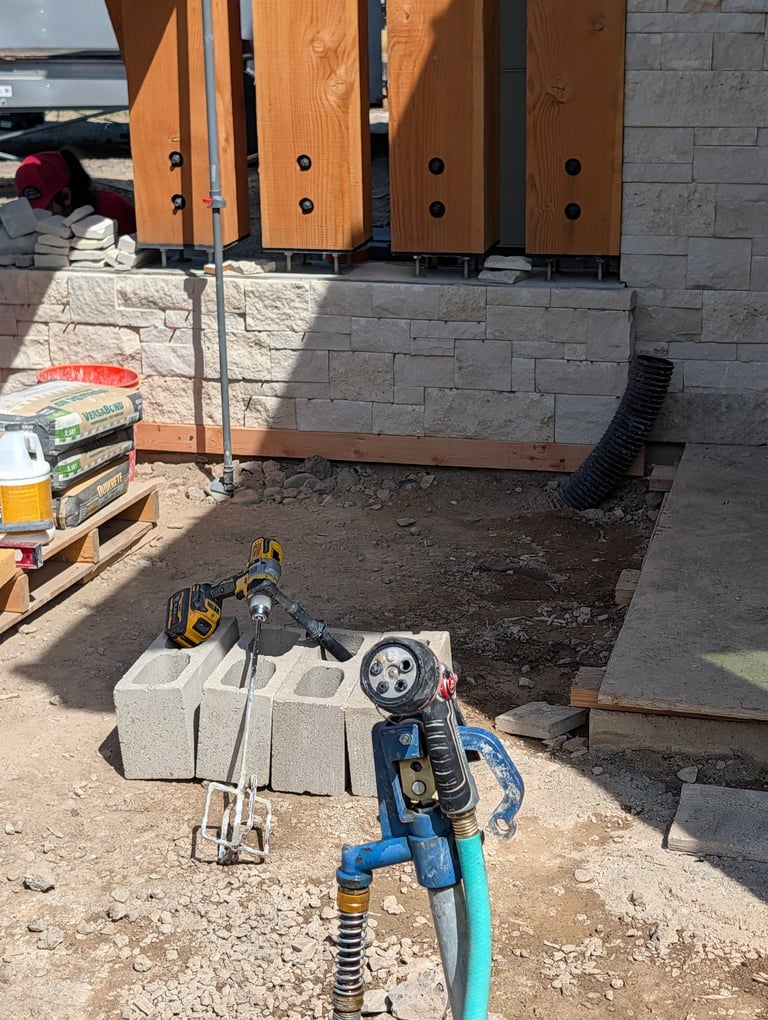 Blue motorcycle parked on construction site with wooden speaker cabinets and concrete blocks visible in background