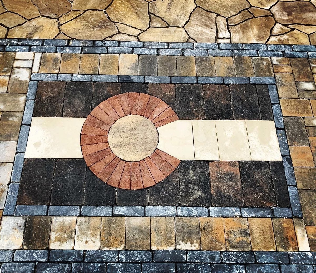 Decorative tile floor with geometric pattern featuring a red circular medallion on black and white bands