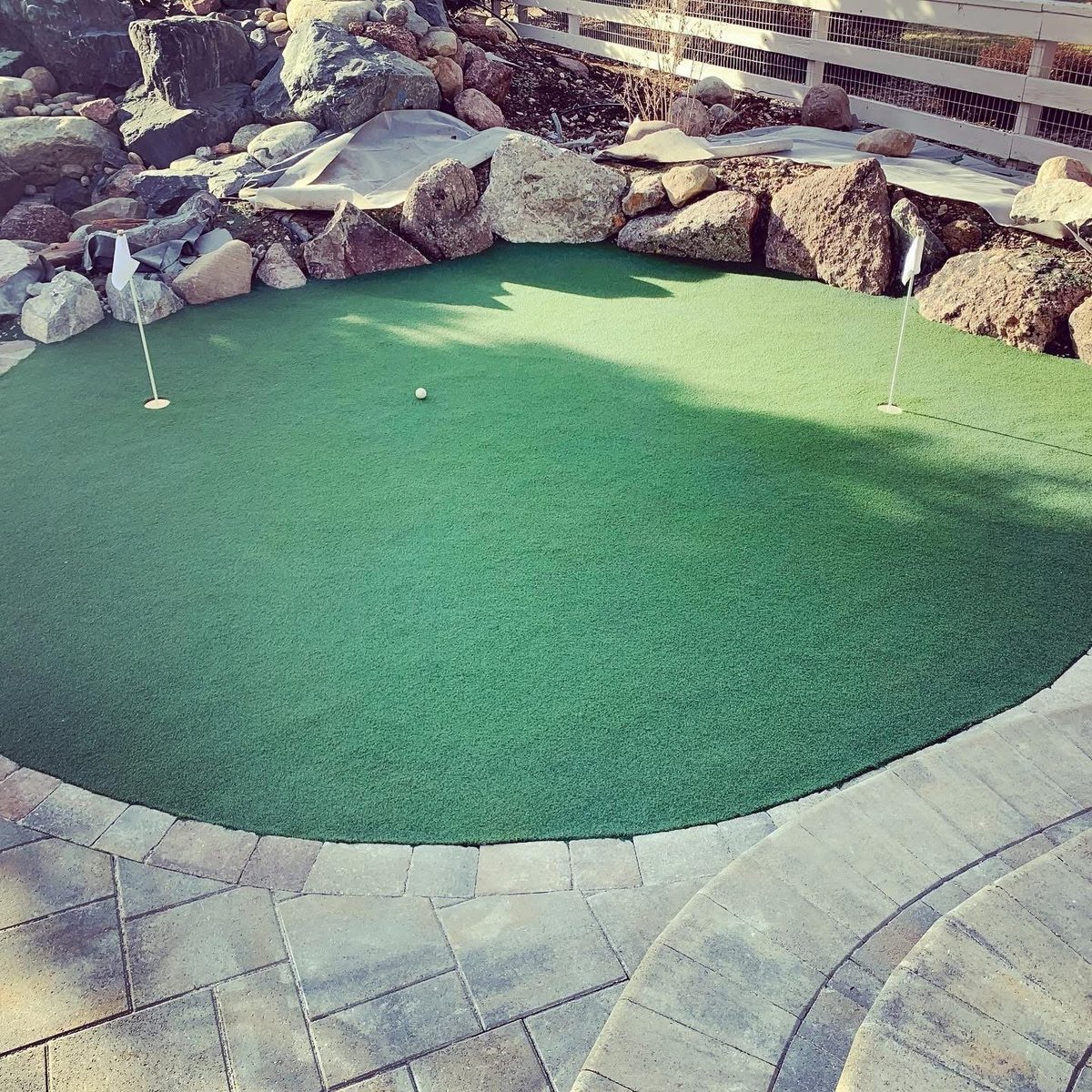 Miniature golf putting green with bright green turf, flagsticks, and decorative rock formations