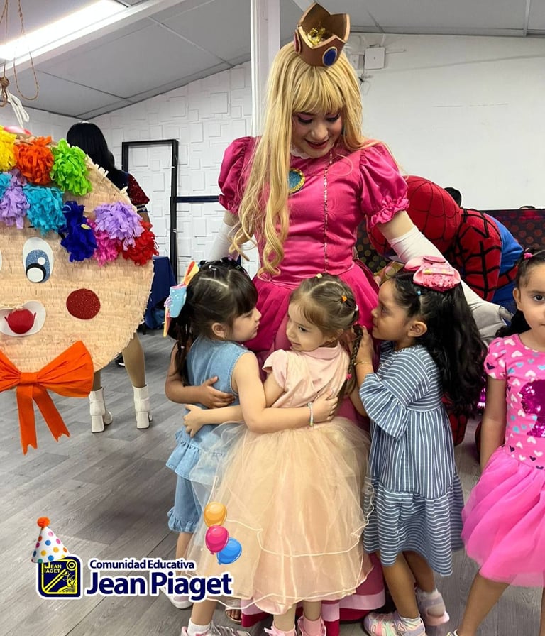 A performer in a pink dress and blonde hair entertains young children at a birthday party, with a colorful handmade clown decoration visible in the background.
