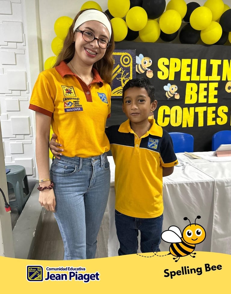 Two students in yellow uniforms at a Spelling Bee Contest, with yellow and black balloons and signage in background
