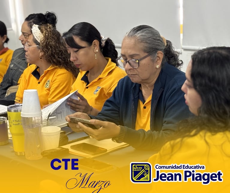 Group of educators in yellow and navy uniforms seated at a table during a CTE March event at Comunidad Educativa Jean Piaget school