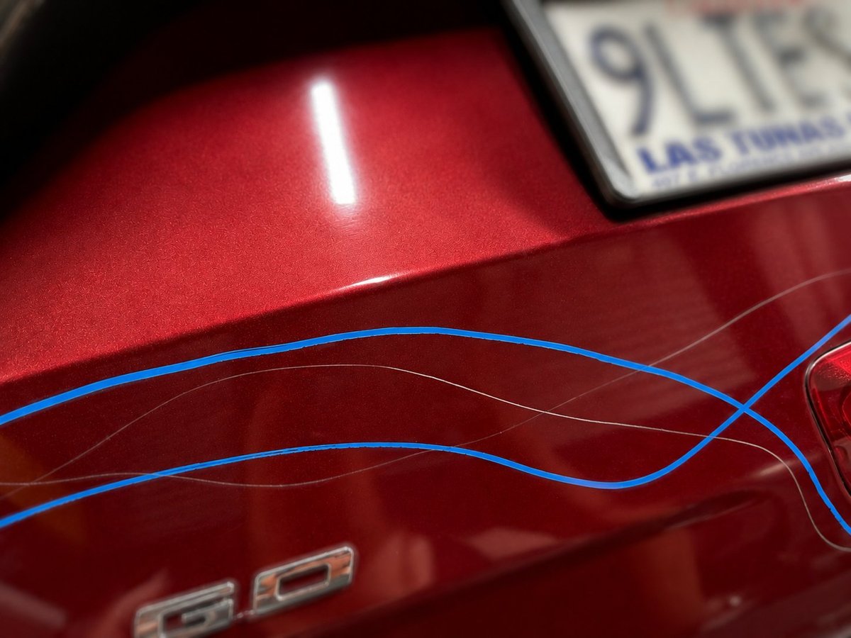 Close-up of red car hood with glowing blue neon trim lines — a Best Collision Center restoration