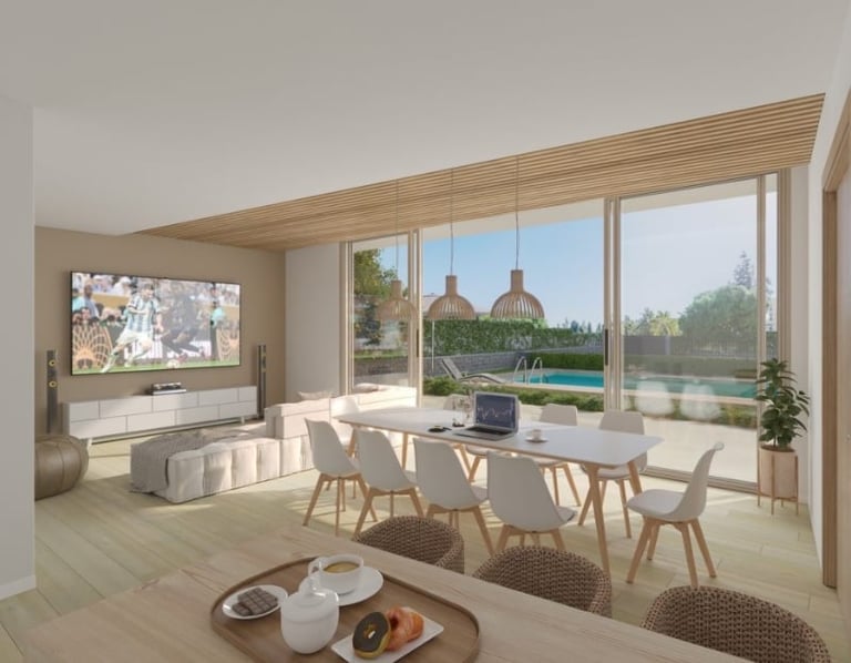 Modern open-plan living and dining space with floor-to-ceiling windows overlooking a water view and outdoor terrace with lounge seating