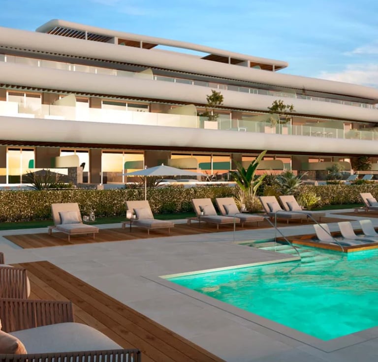 Modern residential building with pool, lounge chairs, and landscaping viewed from poolside during daytime