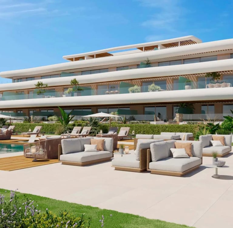 Modern multi-story residential building with curved white architecture, terrace with lounge seating, pool, and manicured garden on sunny day