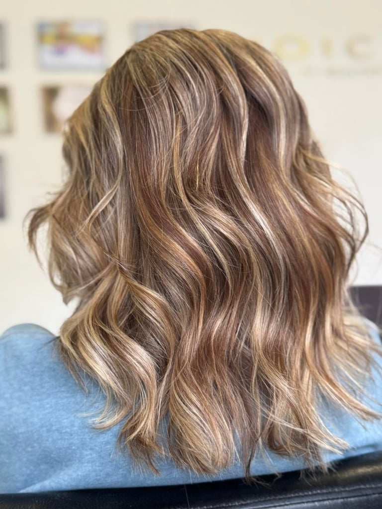 Back view of shoulder-length wavy hair with warm blonde balayage highlights and dimensional brown tones