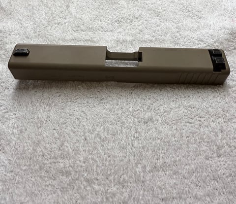 Tan slide assembly for a semi-automatic pistol displayed on a textured white surface