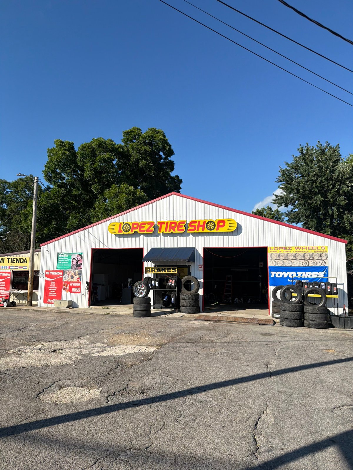 Lobo Tire Shop storefront with red metal roof, open bays displaying tires and wheels outside