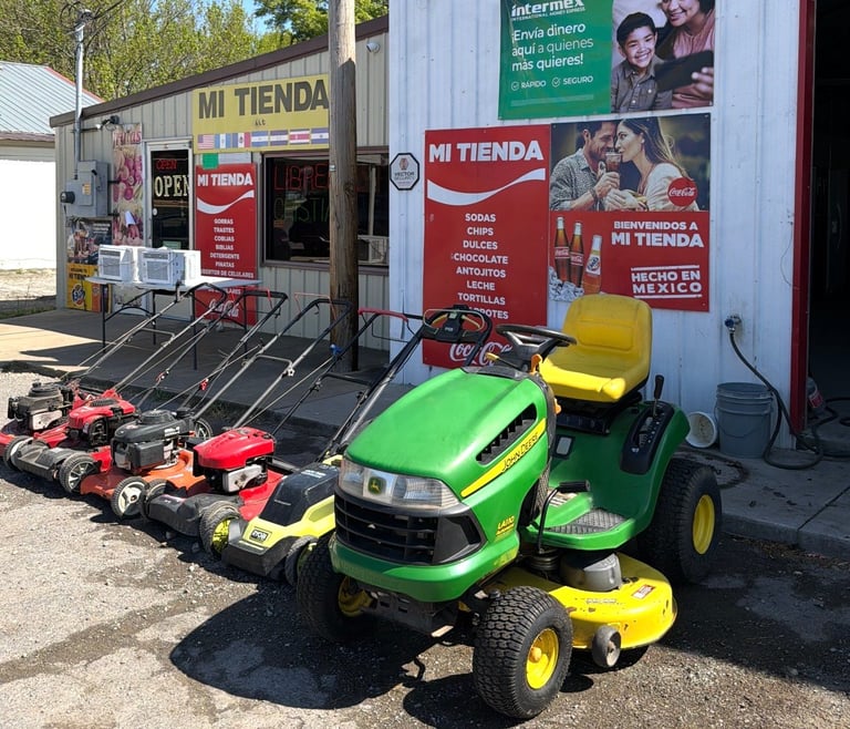 Lawn mowers and garden equipment displayed outside a red and white Mi Tienda hardware store.