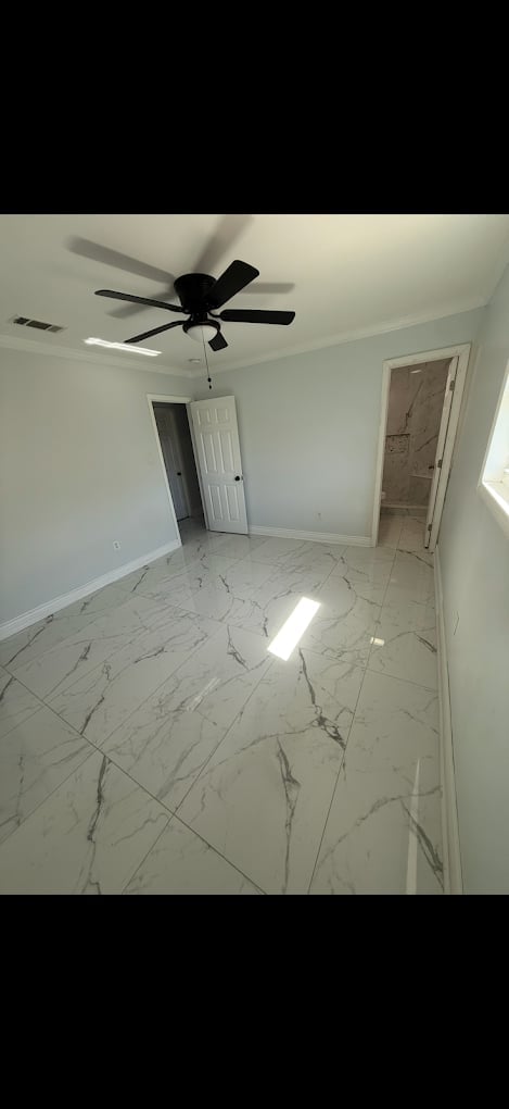 Empty room with white marble tile flooring, light gray walls, black ceiling fan with light fixture, and two white doors leading to other rooms