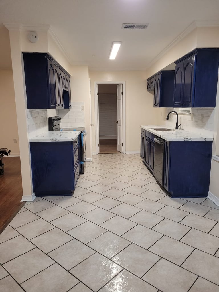 Modern galley kitchen with navy blue cabinetry, white subway tile backsplash, and light tile flooring