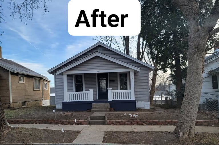 After renovation: Blue and white single-story house with front porch and brick foundation on residential street