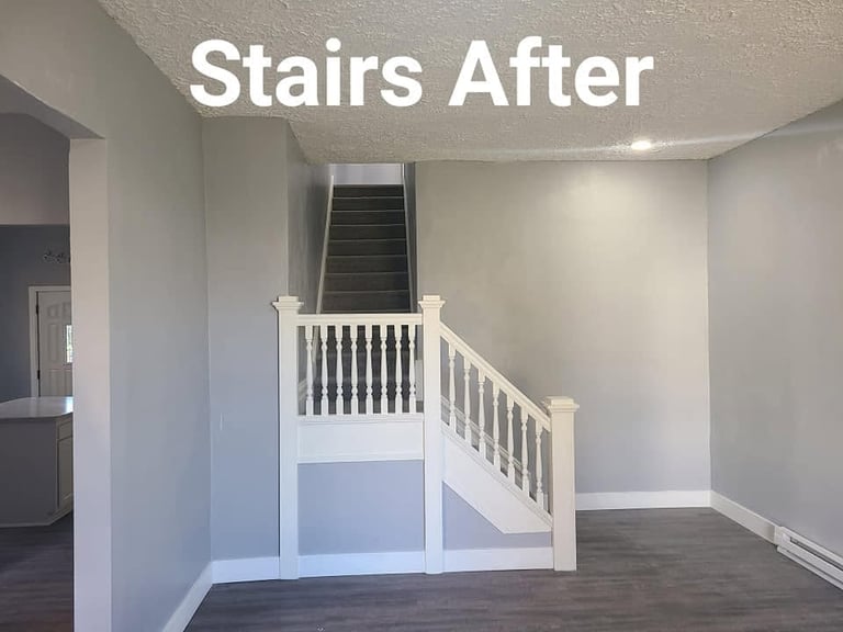 White wooden staircase with railings in renovated interior space with gray walls and dark flooring