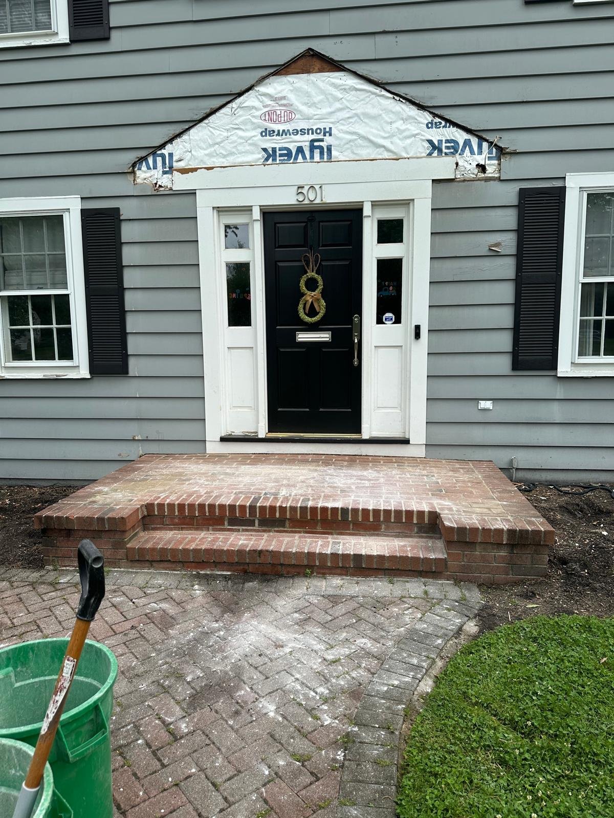 House exterior with gray siding, white trim front door with gold wreath, brick steps, and number 501 above entrance