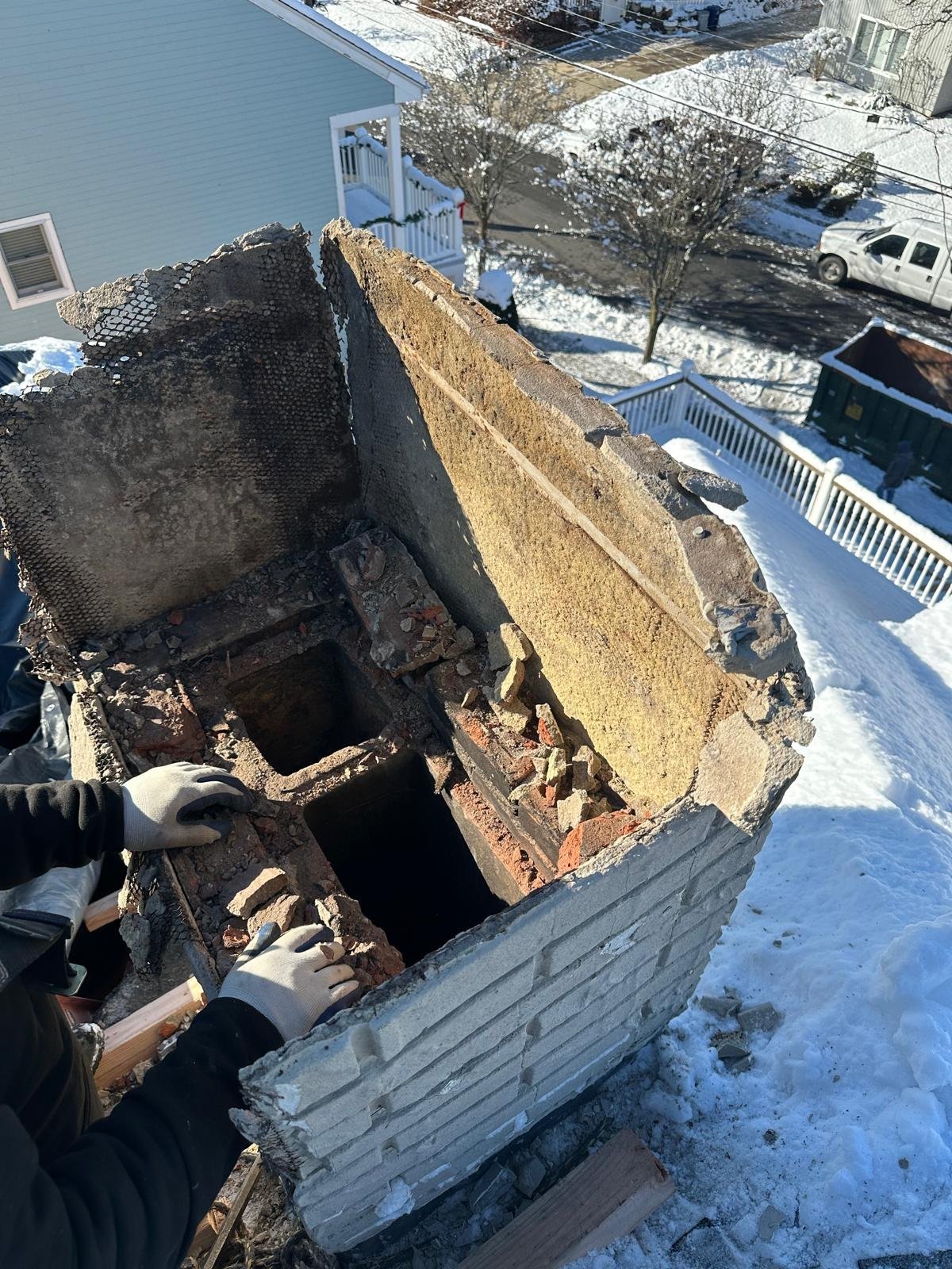 Overhead view of an open cargo truck bed loaded with hay, parked in a snowy residential area near water