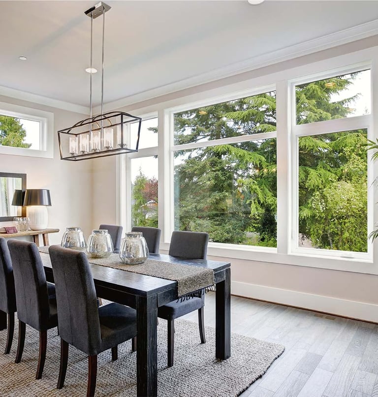 Modern dining room with large impact windows overlooking green landscape