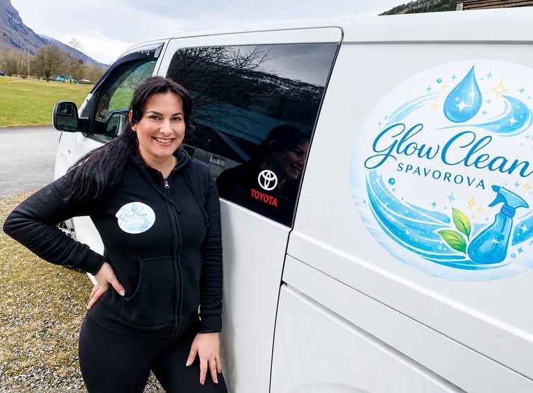 Woman in black jacket smiling next to white Glow Clean Savorova service van in a grassy outdoor area