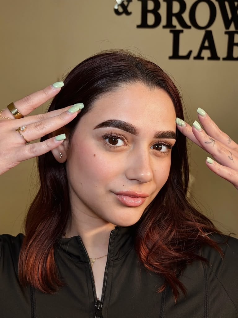 Woman demonstrating with styled hair and makeup against beige background