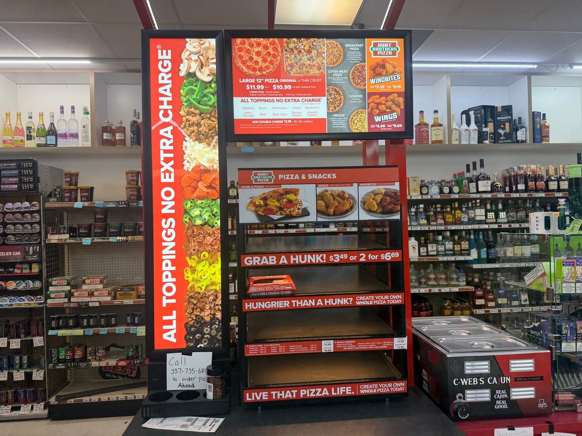 Hunt Brothers Pizza in-store menu board showing pizzas, wings, and pricing for Large, Original, and Thin crust pizzas