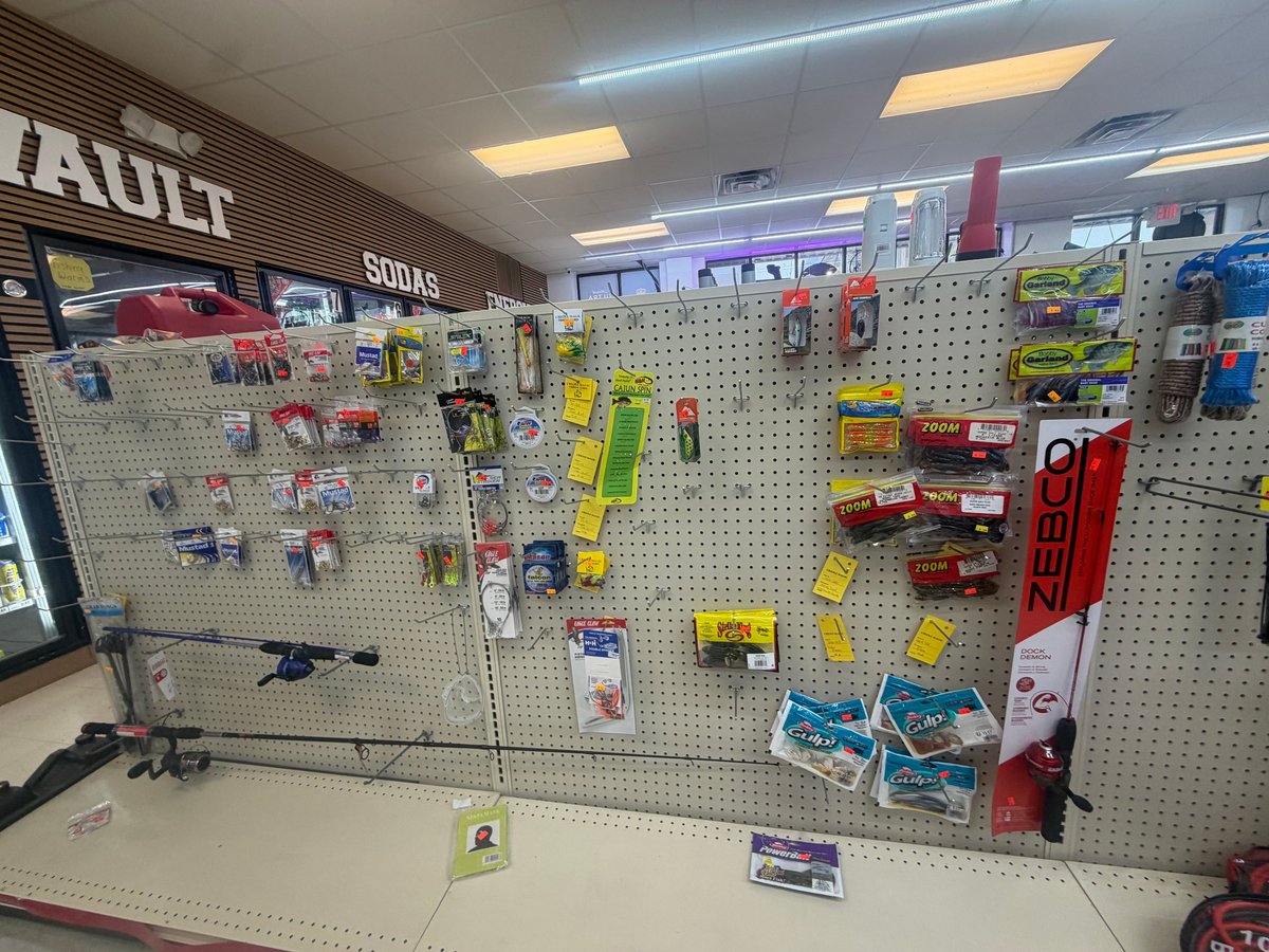 Hardware store display wall with pegboards holding various fishing tackle, tools, and supplies under bright overhead lighting