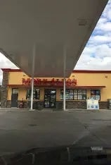 Storefront with large gray overhang structure above yellow building entrance with glass doors and windows