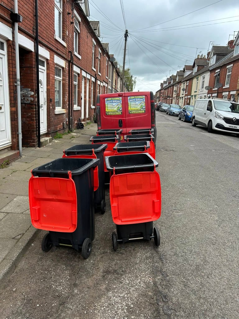 Row of red and black delivery carts parked on a residential street with brick terraced houses in the background