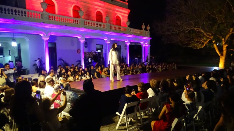 Pasarela al aire libre con el público sentado bajo un edificio histórico iluminado en rojo y morado