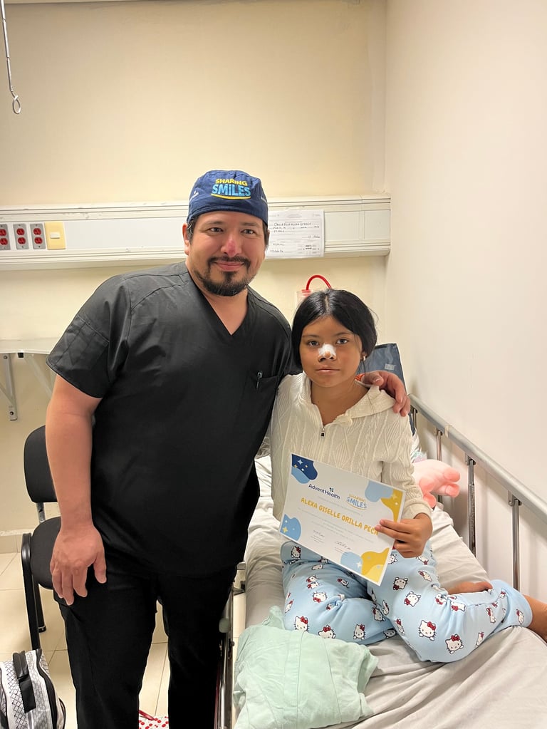 Médico con gorro azul posando junto a una niña en cama de hospital con pijama durante la jornada