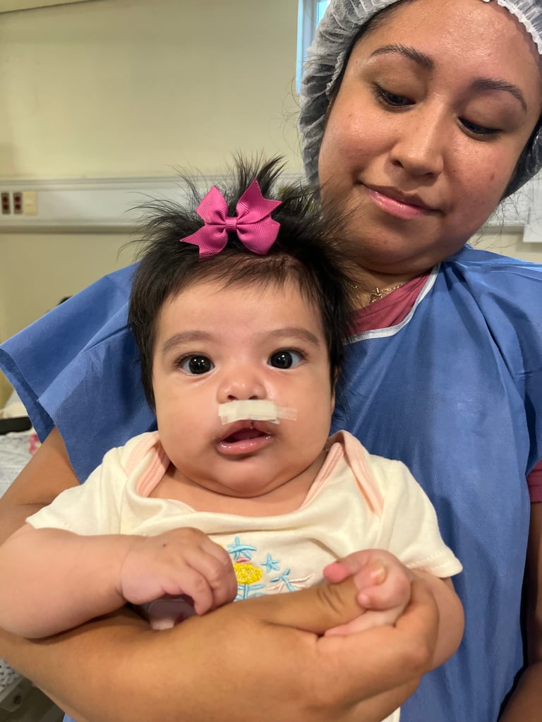 Trabajadora de la salud sosteniendo a una bebé con un moño rosa en el cabello