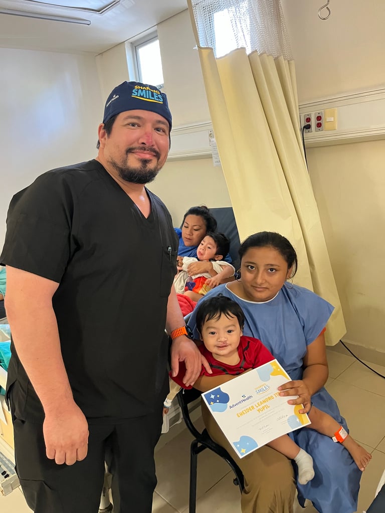 Médico con uniforme quirúrgico posa con una mujer y dos niños mostrando un certificado de la jornada