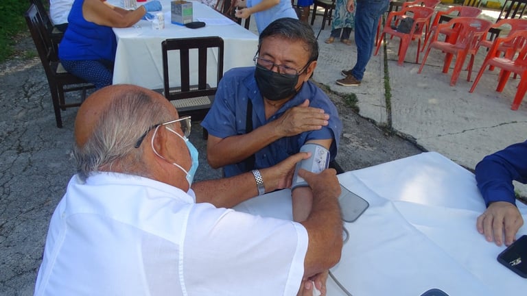 Adulto mayor recibiendo toma de presión con apoyo de un especialista