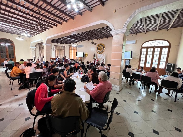 Vista general del salón durante una sesión del curso con asistentes en mesas redondas