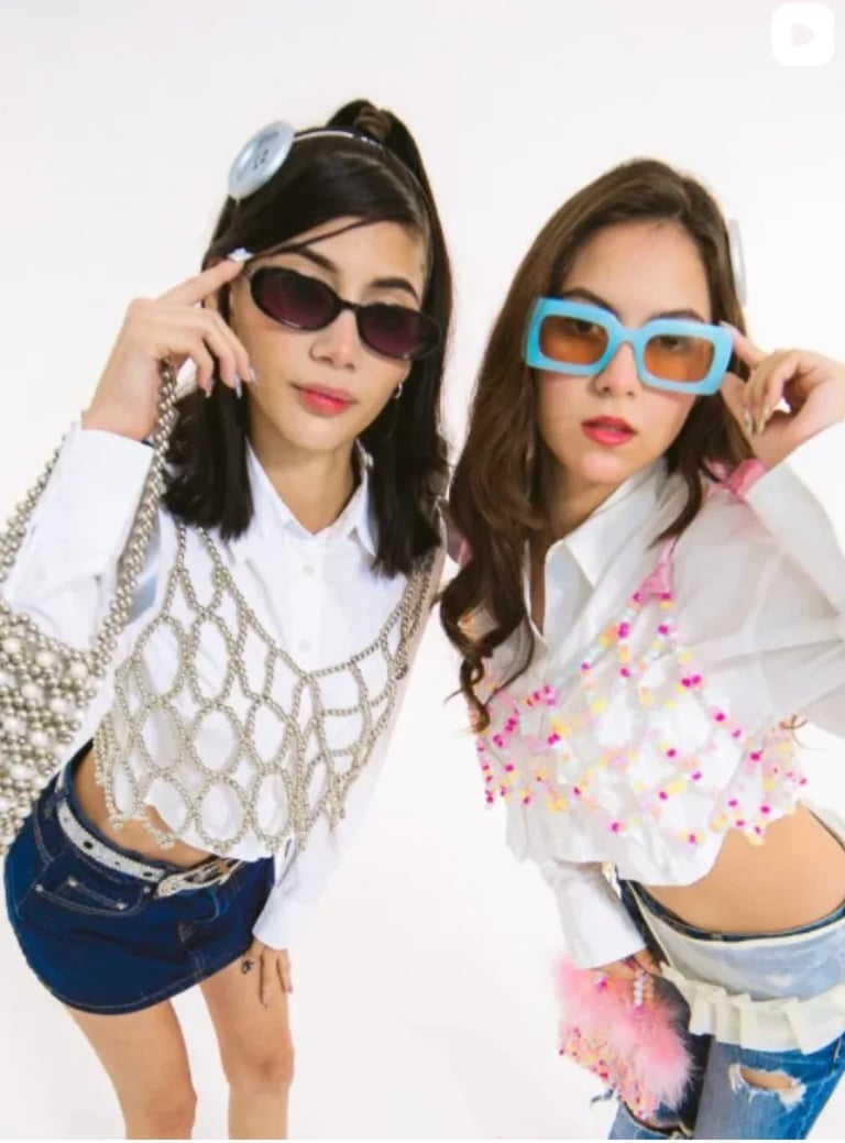 Dos jóvenes modelos posando con lentes de sol coloridos y tops cortos sobre fondo blanco, propuesta de EZER