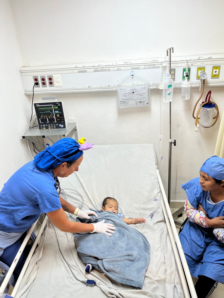 Dos profesionales de la salud con uniforme azul examinan a un bebé en una cama hospitalaria