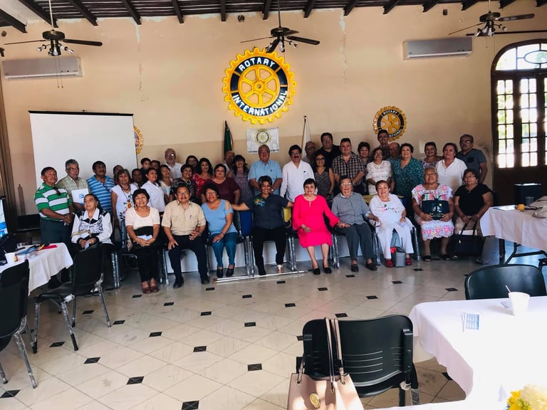 Foto grupal de los asistentes al curso frente al escudo de Rotary International