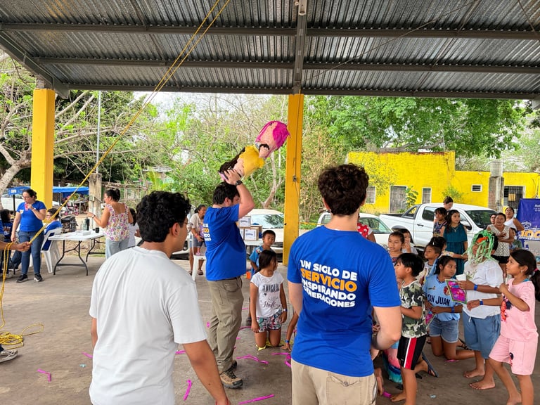 Voluntarios en playera azul jugando con niños en Chinkilá