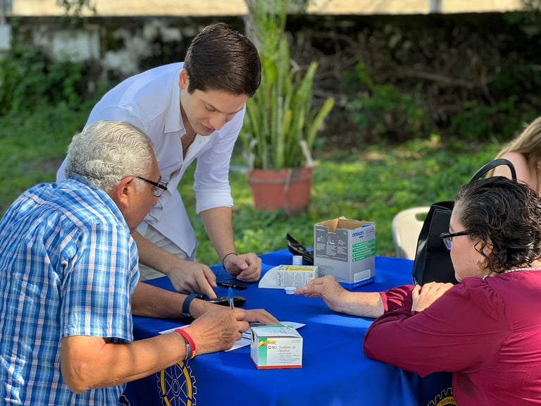 Voluntario Rotary orientando a asistentes en mesa azul al aire libre