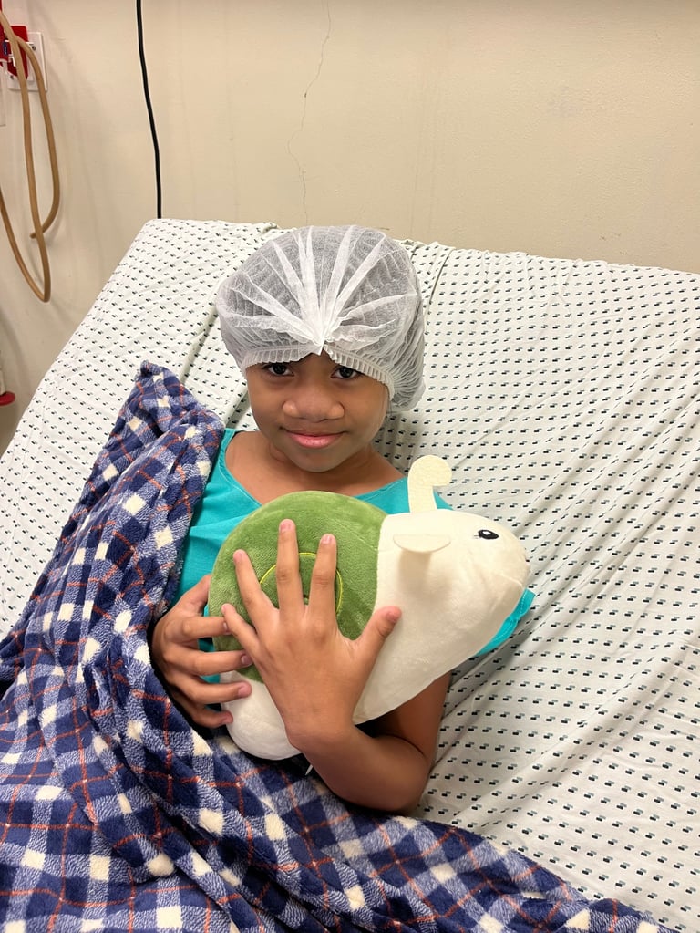 Niña con gorro quirúrgico abrazando un peluche blanco y verde para sentirse acompañada en el hospital