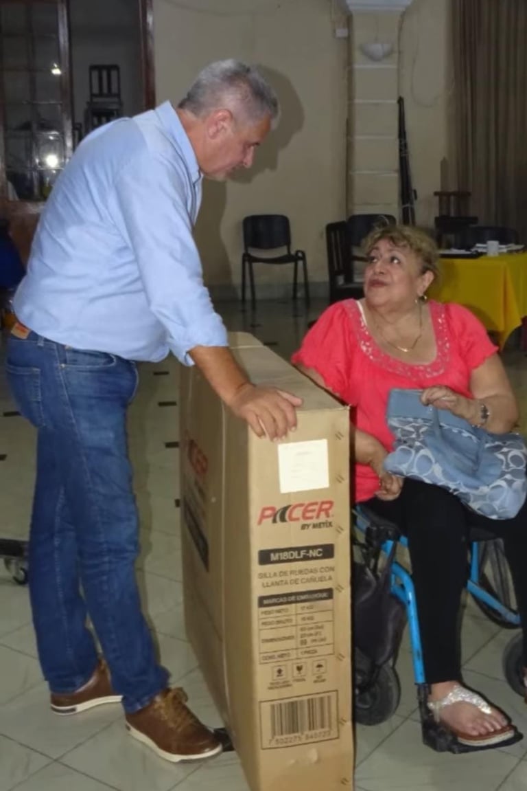 Hombre de camisa azul junto a una señora sentada mostrando juntos una caja grande etiquetada ACER durante la entrega
