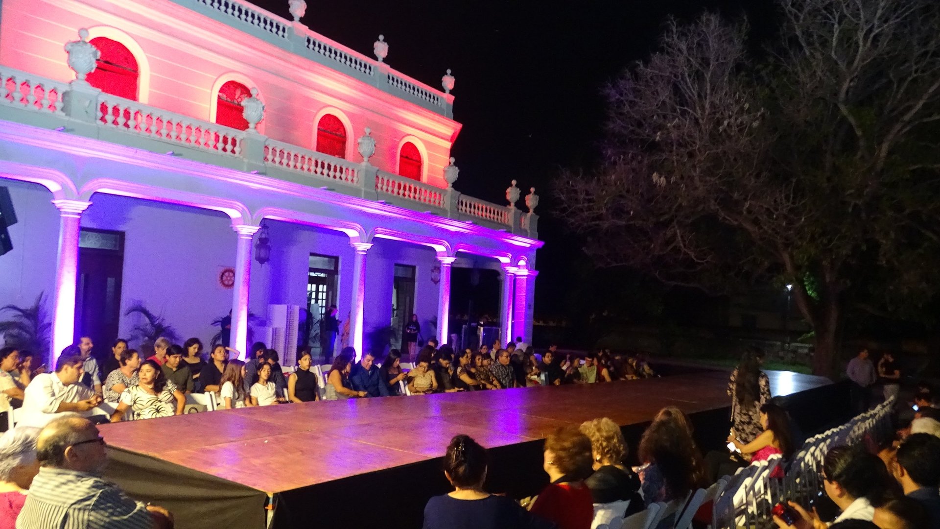 Edificio colonial de Mérida iluminado en rosa y morado durante una pasarela nocturna al aire libre