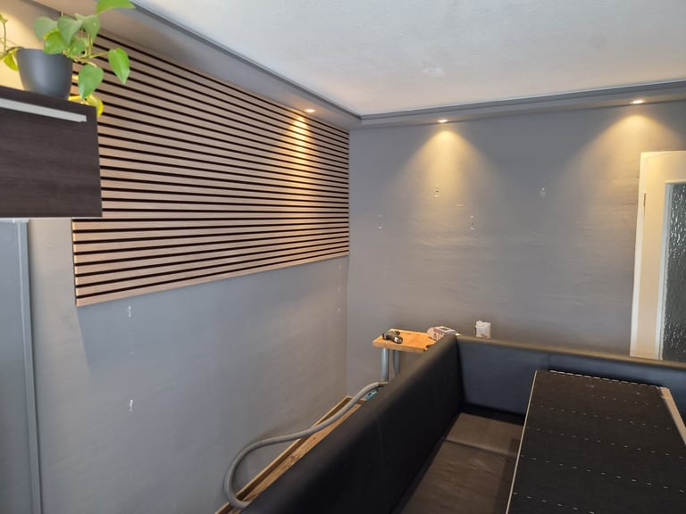 Modern office interior with striped wooden wall accent, blue walls, recessed lighting, and black desk or counter