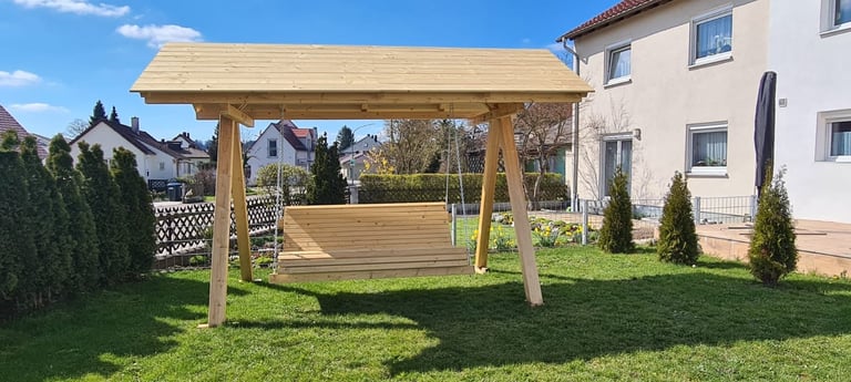 Wooden pergola with swing in backyard of residential home on sunny day