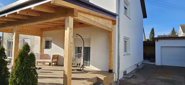 Modern house with wooden patio pergola, outdoor furniture, and landscaping under clear blue sky