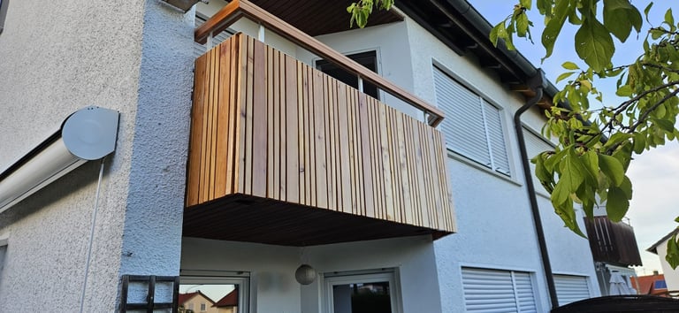 Modern blue house with wooden slatted balcony railing and climbing vines overhead