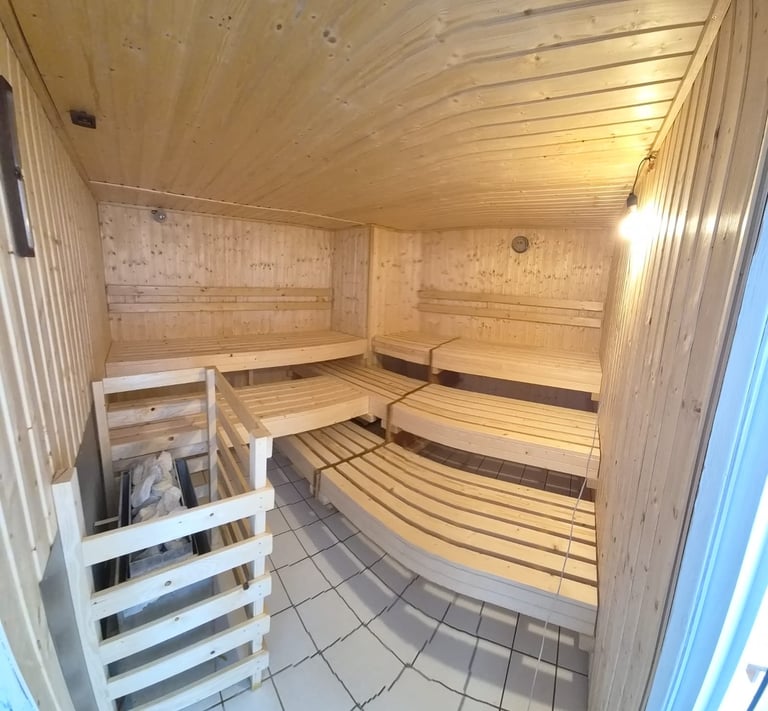 Interior of a wooden sauna with tiered benches, tile floor, and overhead lighting
