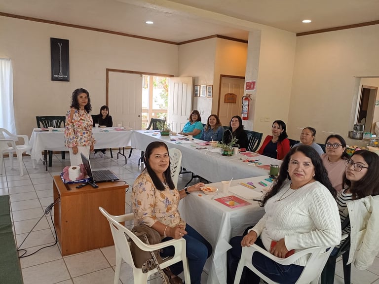 Grupo de mujeres sentadas en mesas en una sala comunitaria durante una presentación o reunión