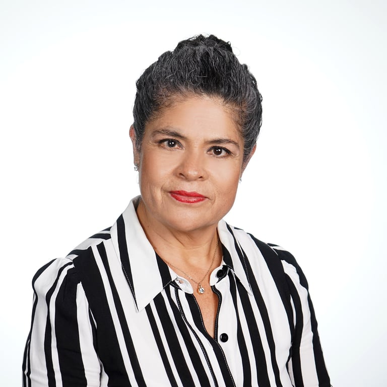 Retrato profesional de Gabriela Durán Valenzuela, mujer de cabello gris recogido, con camisa blanca y negra a rayas, sonriendo con confianza